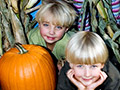 Smiling children in the corn maze next to a pumpkin